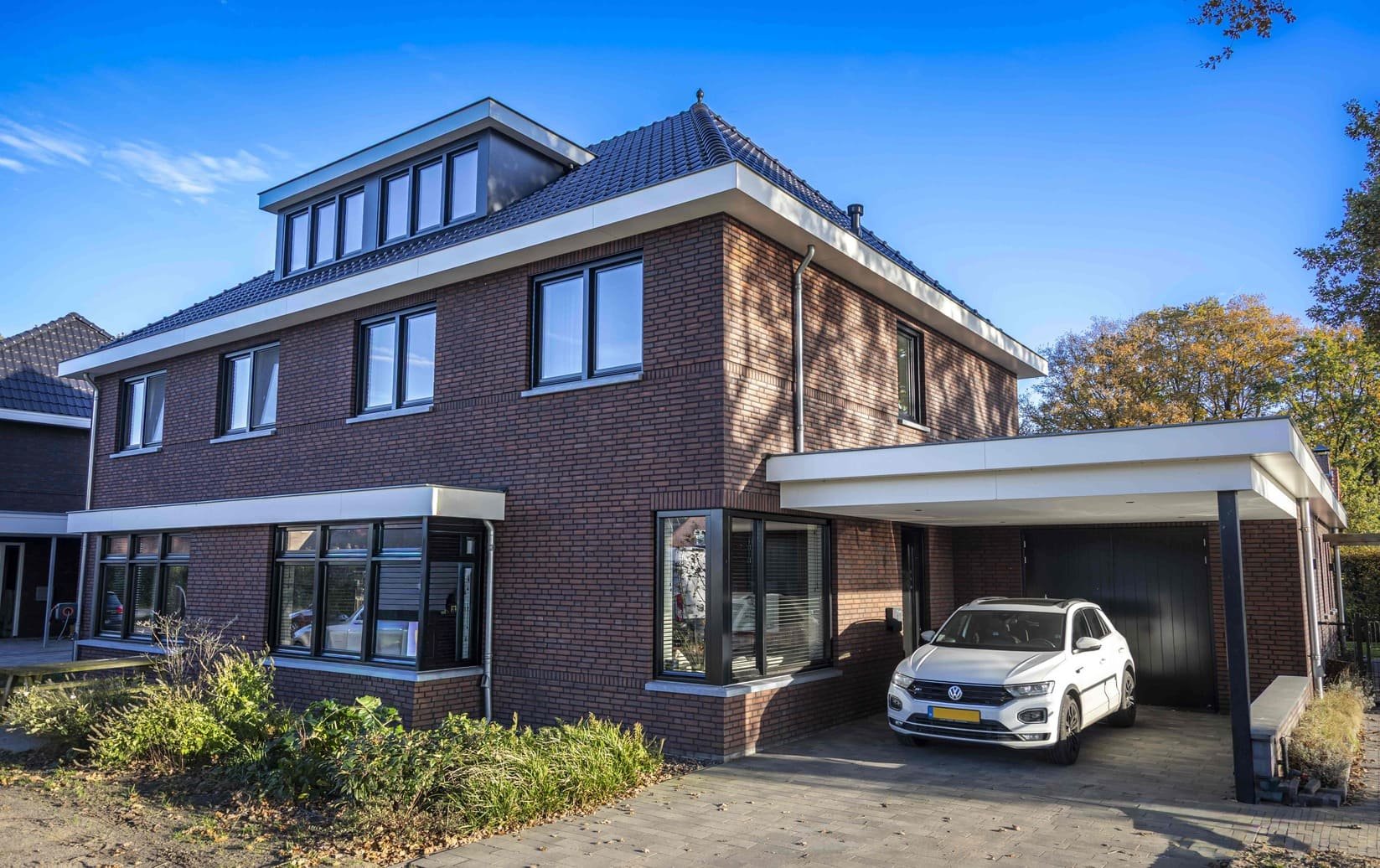 Woning met bakstenen gevel, aanbouw en carport
